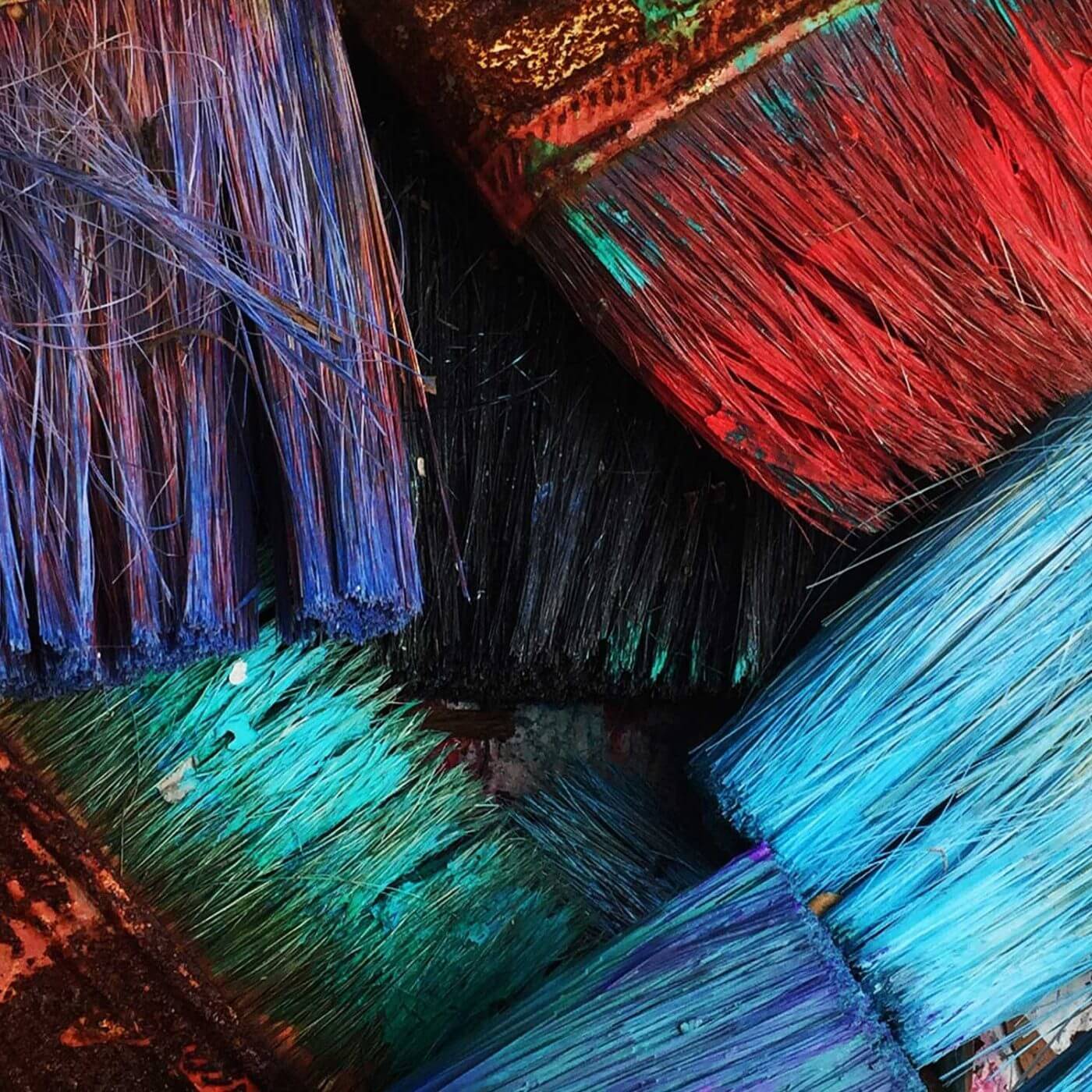 A closeup of paintbrushes with various colors of paint on them.