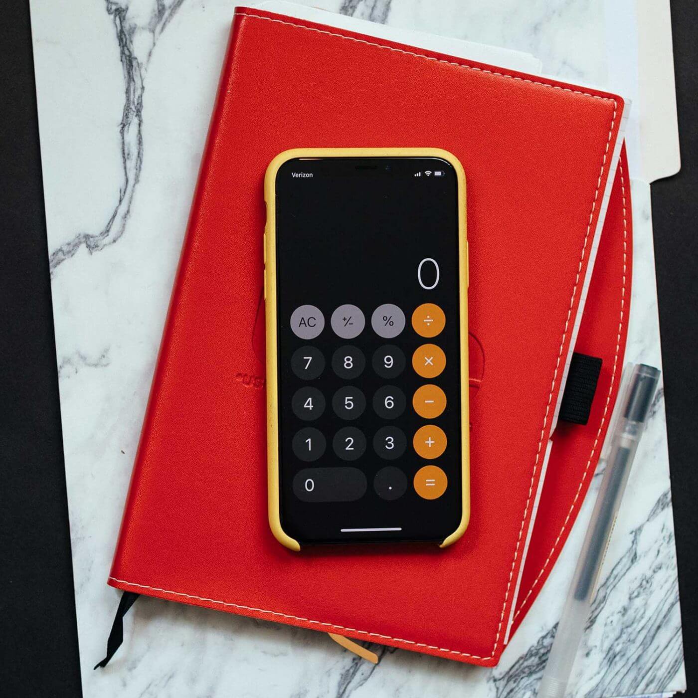 A smartphone with a calculator app open sitting on top of a notebook.
